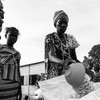 امرأة تقسم الذرة التي حصلت عليها كحصة غذائية شهرية في مخيم المهد للنازحين في جوبا، جنوب السودان.