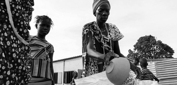 امرأة تقسم الذرة التي حصلت عليها كحصة غذائية شهرية في مخيم المهد للنازحين في جوبا، جنوب السودان. (الصورة: النيلان | بولن تشول)