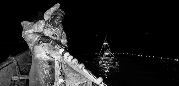 A fisherman retrieves his casted net at night.  (photo: Anthony Ochieng / TonyWild)